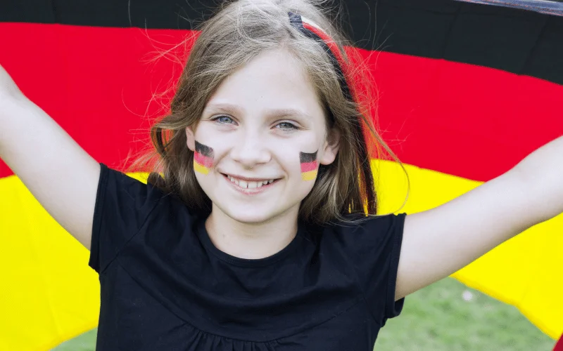Niemiecki dla dzieci od jakiego wieku - uśmiechnięta dziewczynka z flagą Niemiec